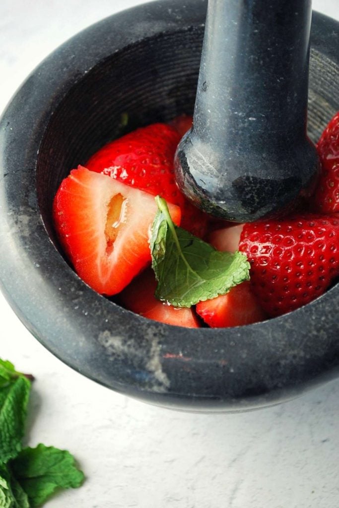 fresh strawberries and mint in a mortar and pestle