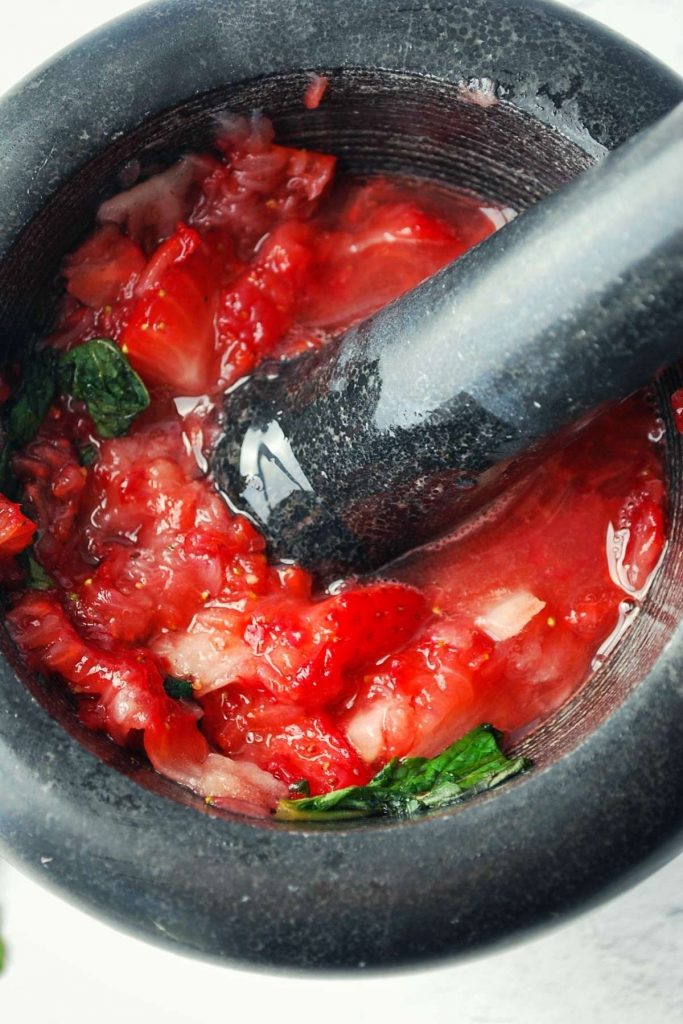 muddled strawberries and mint in a mortar and pestle