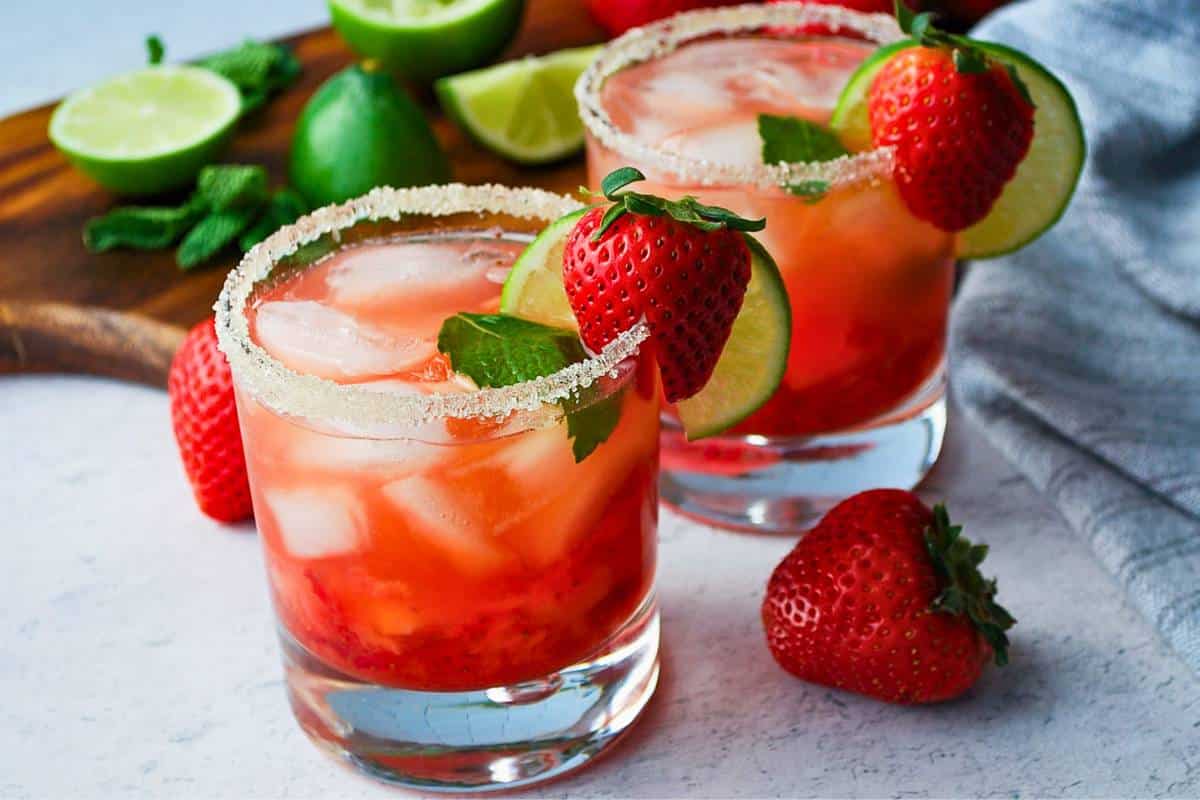 two mojitos with fresh strawberries in low ball glasses