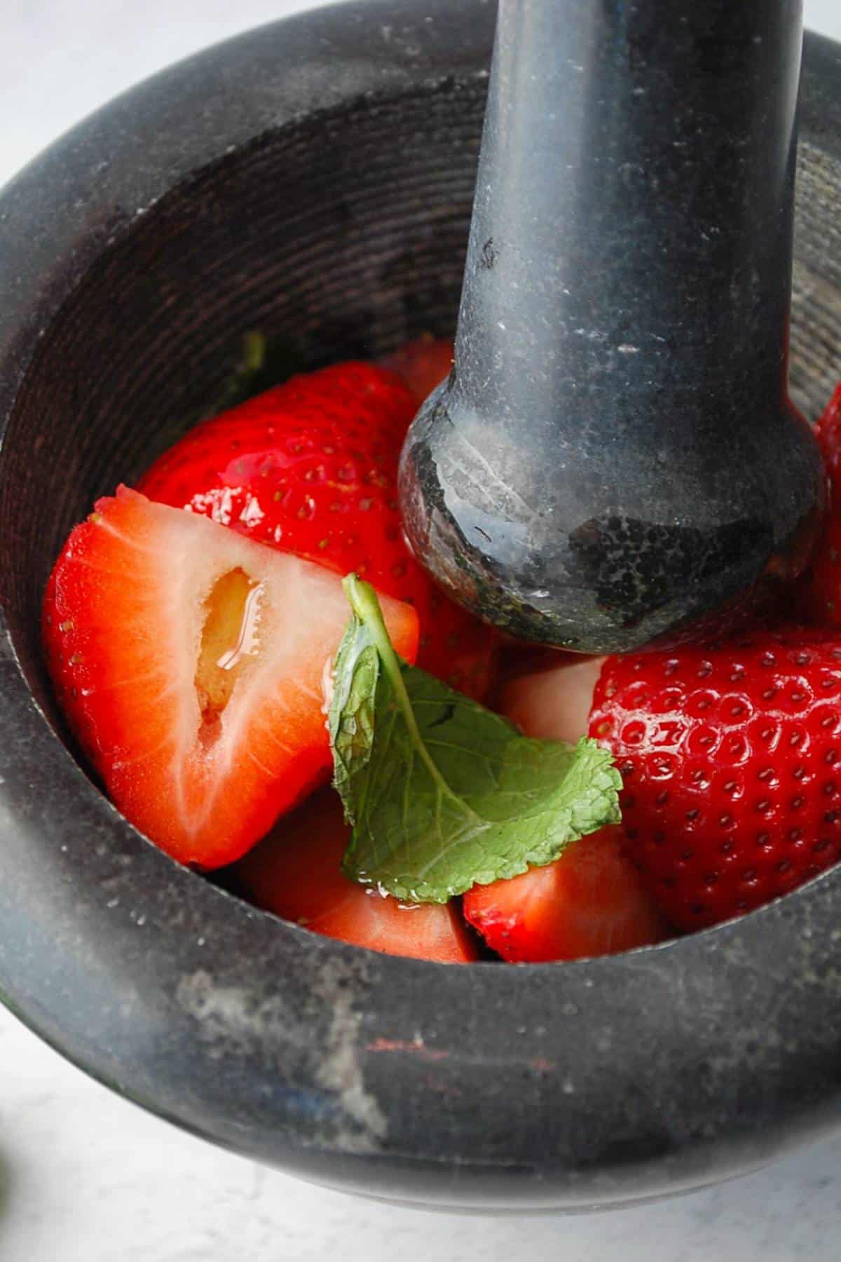 fresh strawberries and mint in a mortar and pestle