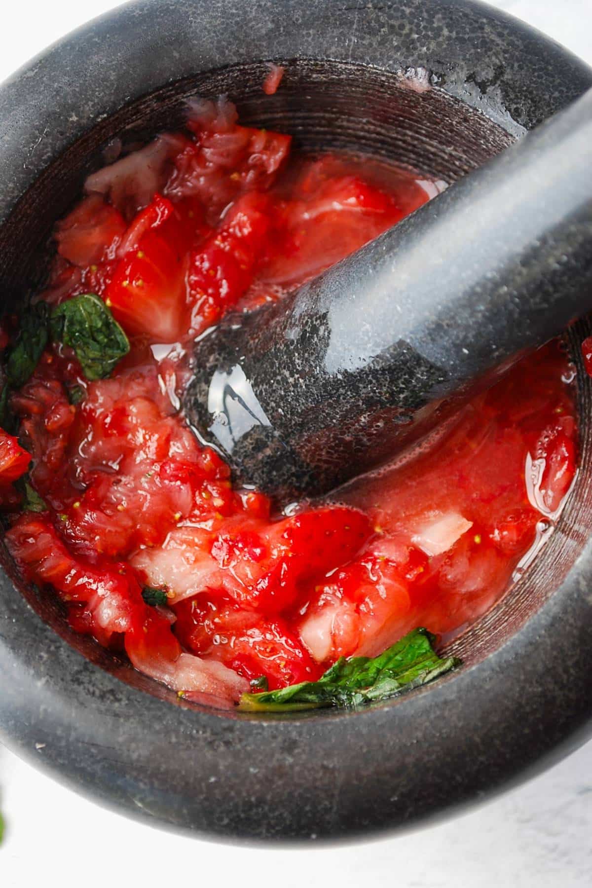 muddled mint and fresh strawberries in a mortar and pestle