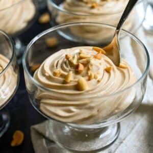 swirled peanut butter mousse in dessert glasses topped with chopped peanuts