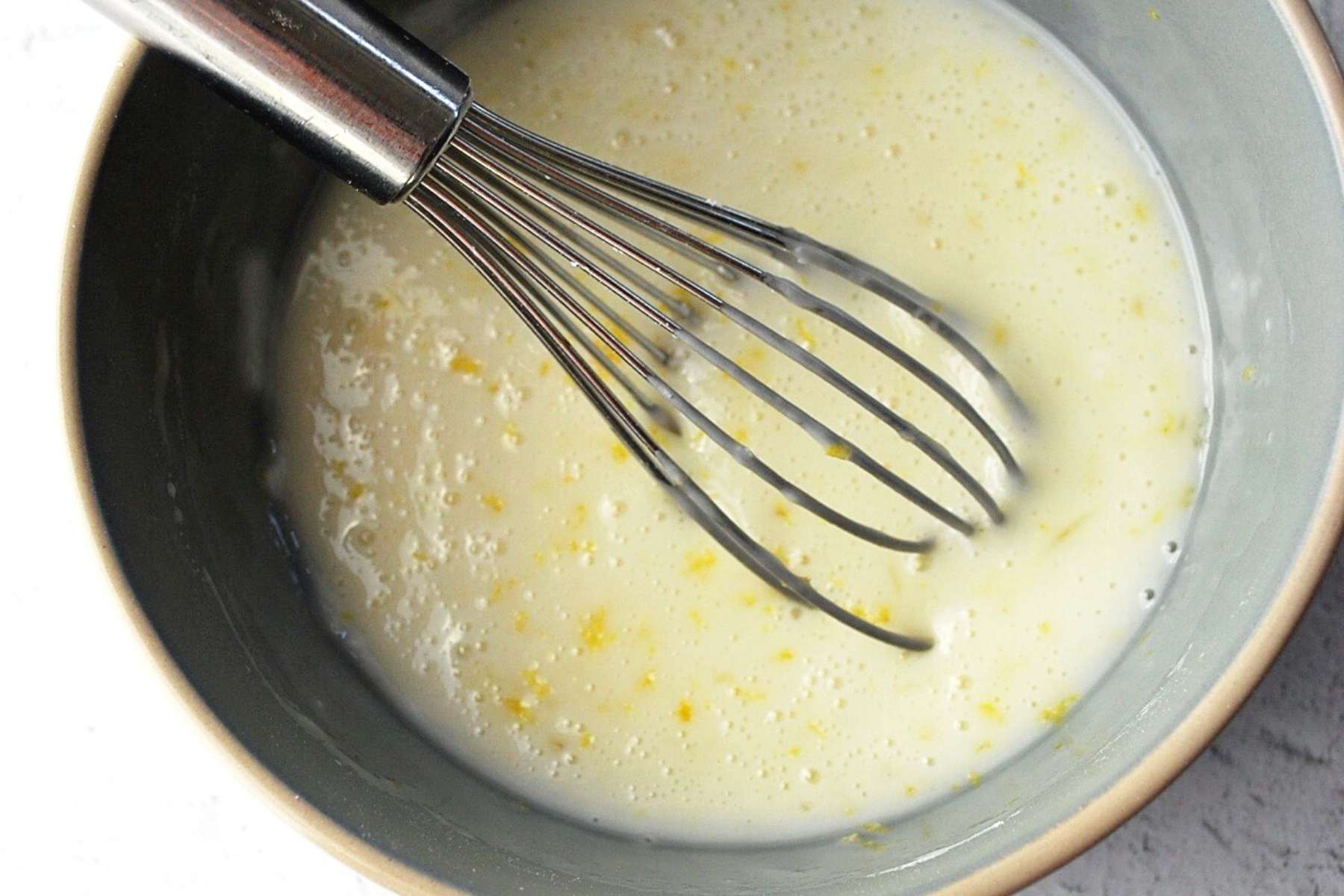 lemon cookie glaze in a bowl with a whisk