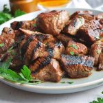 close up of steak tips on a gray plate with fresh parsley