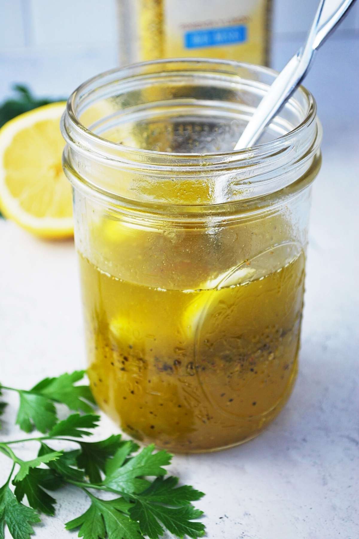 jar of lemon pepper marinade with fresh parsley and sliced lemon in the background