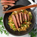 overhead photo of Asian flank steak bowls with chop sticks on top