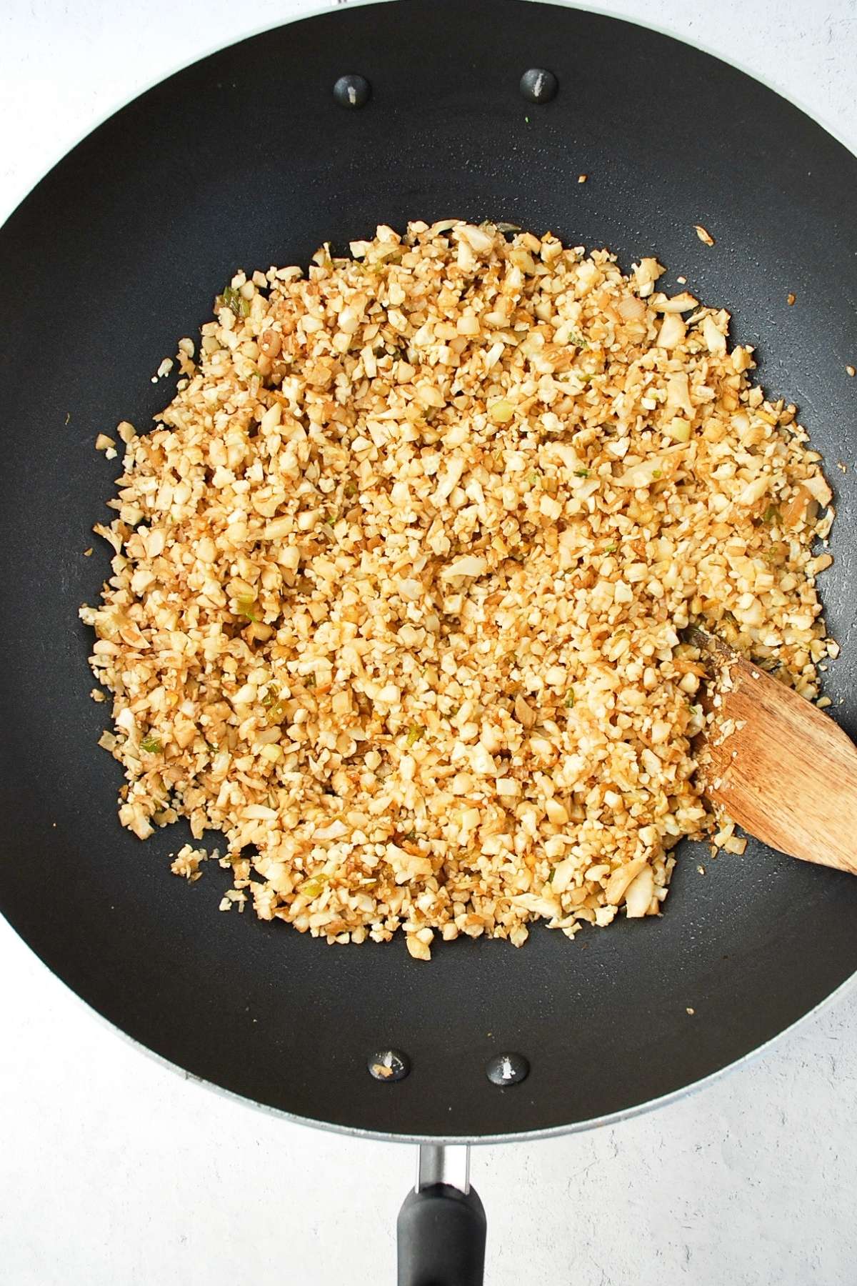 cauliflower rice cooking in a wok with soy sauce