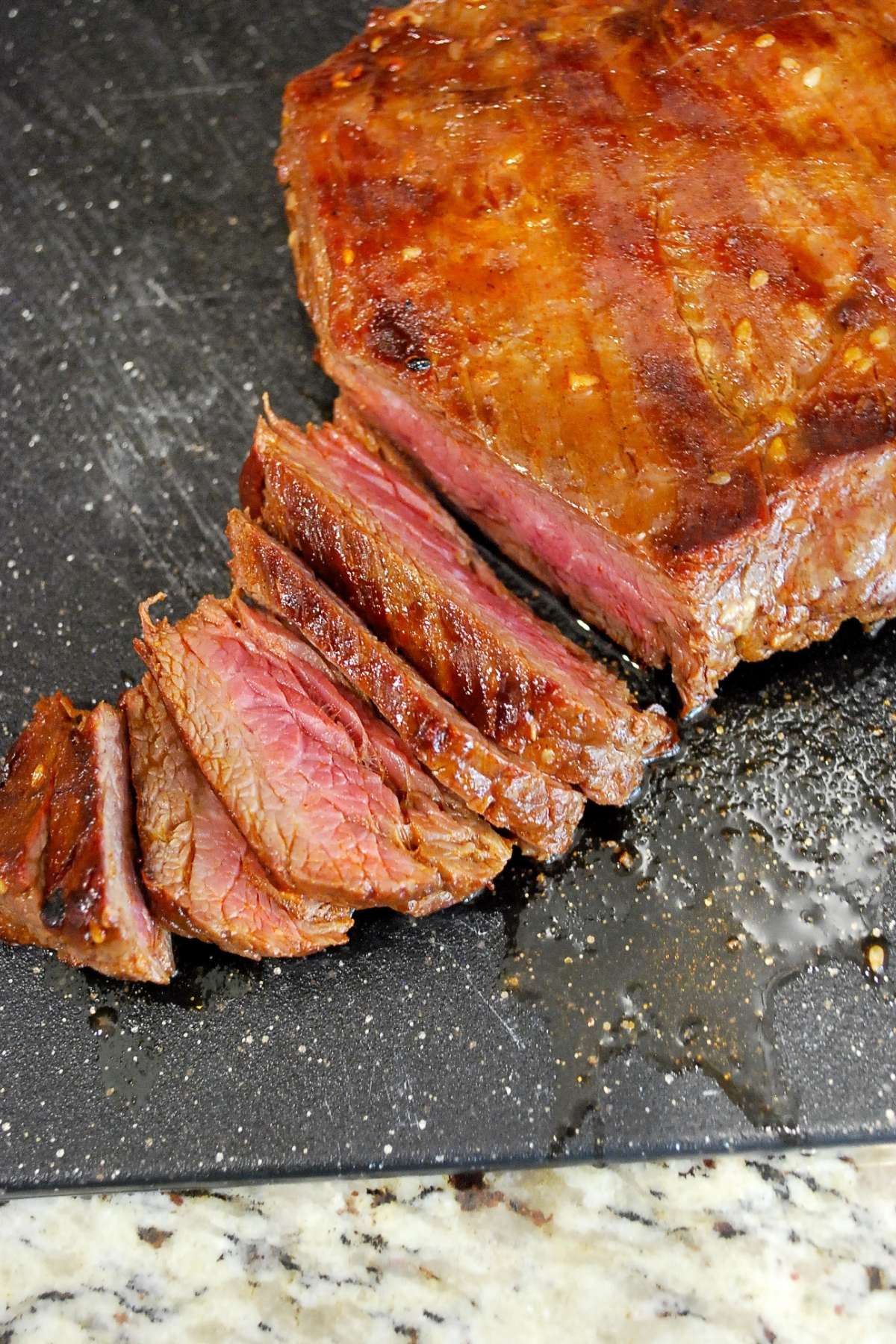 sliced cooked flank steak on a cutting board