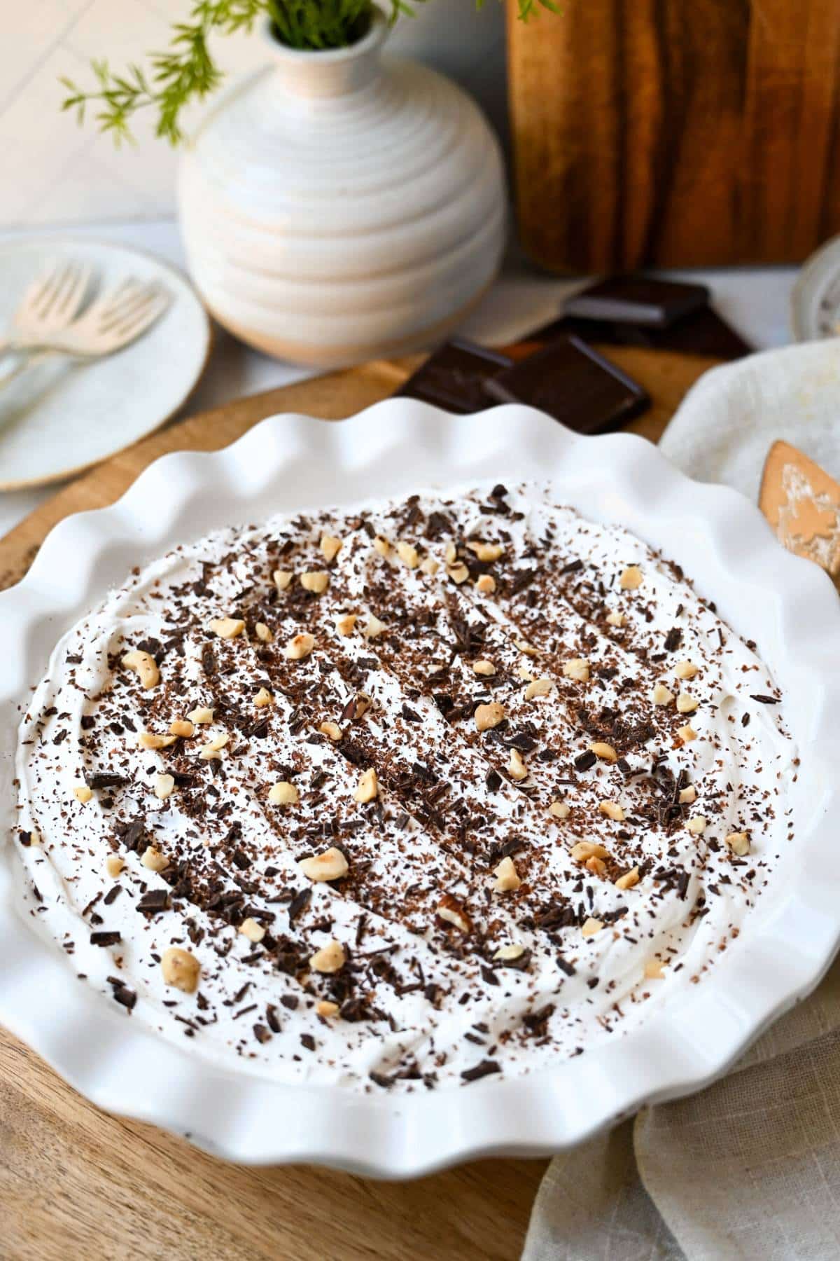 a cool whip topped hazelnut pie topped with grated chocolate and chopped hazelnuts 