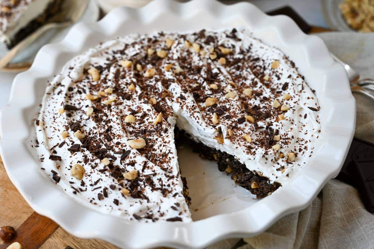 close up of a chocolate hazelnut pie in a pie pan with a slice cut out