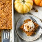 close up of a serving of pumpkin pie oats with whipped cream, nuts, and cinnamon