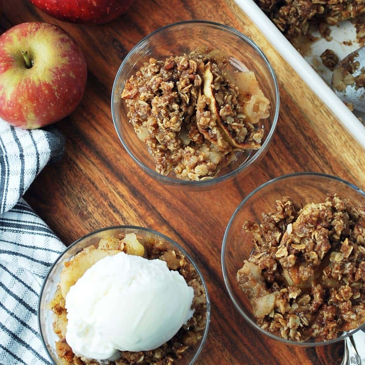 three parfait dishes with sugar free apple crisp with a scoop of ice cream on top of one serving