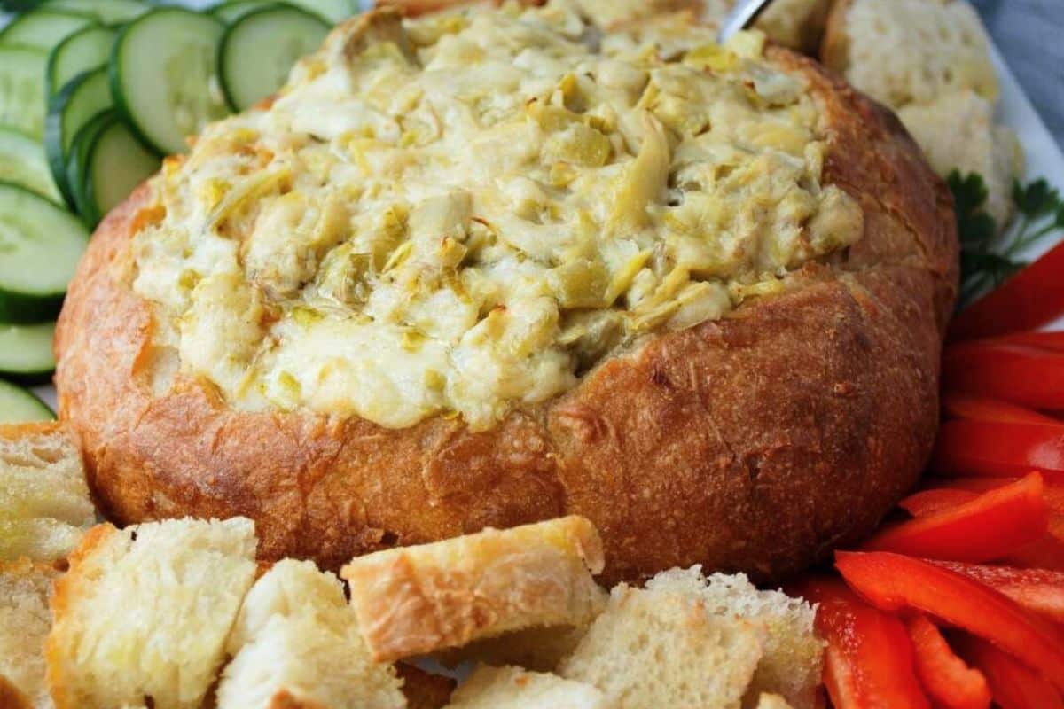 close up of baked jalapeno artichoke dip with bread cubes and veggies