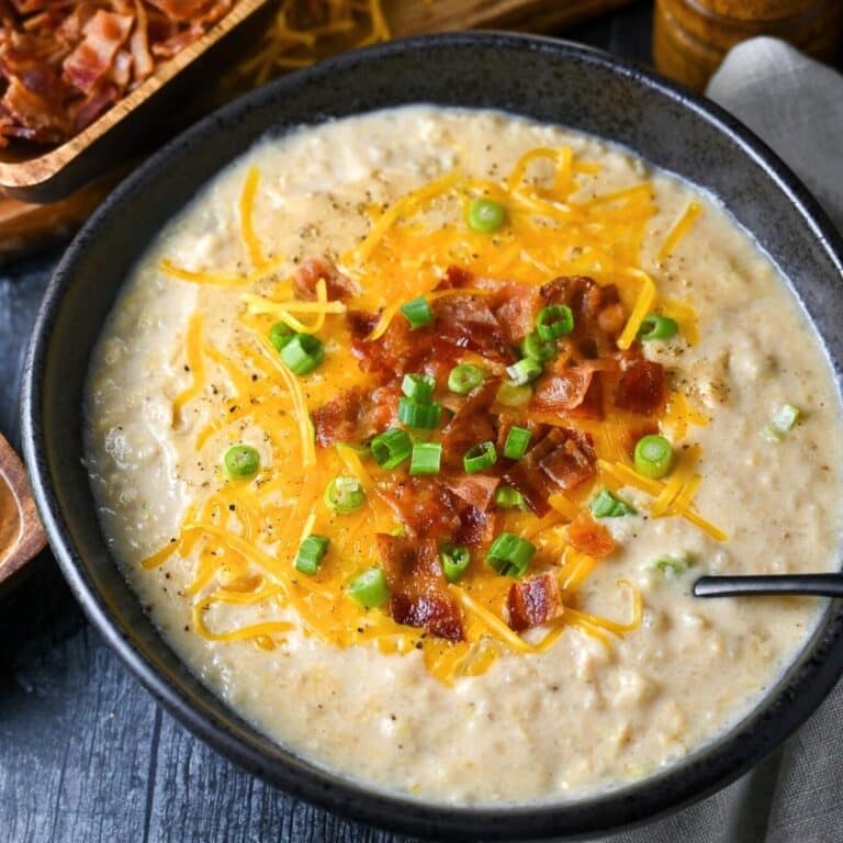 a bowl of potato soup with cheese, bacon, and green onions on top