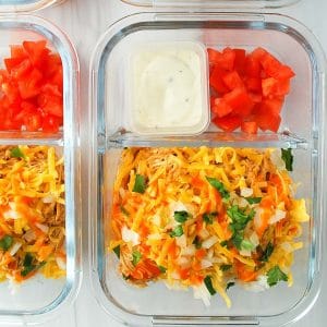 close up photo of two buffalo chicken meal prep bowls with chopped tomatoes and ranch