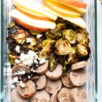 chicken sausage, brussels sprouts and apple slices in a meal prep container