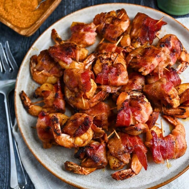 grilled shrimp wrapped in bacon on a plate with a fork next to it
