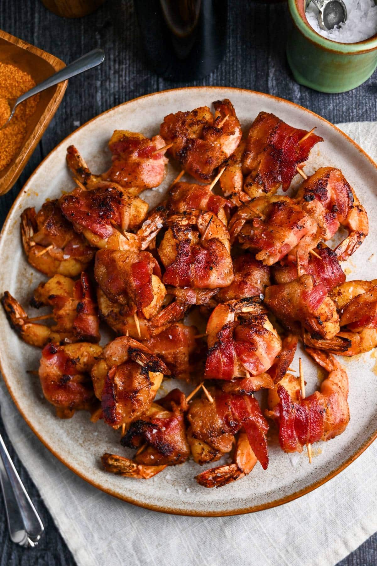 a platter of grilled shrimp with bacon with a napkin