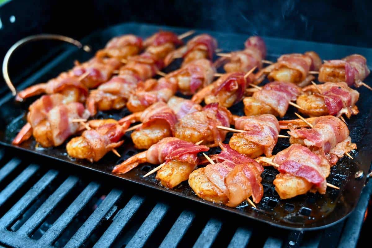 bacon wrapped shrimp cooking on a grill pan