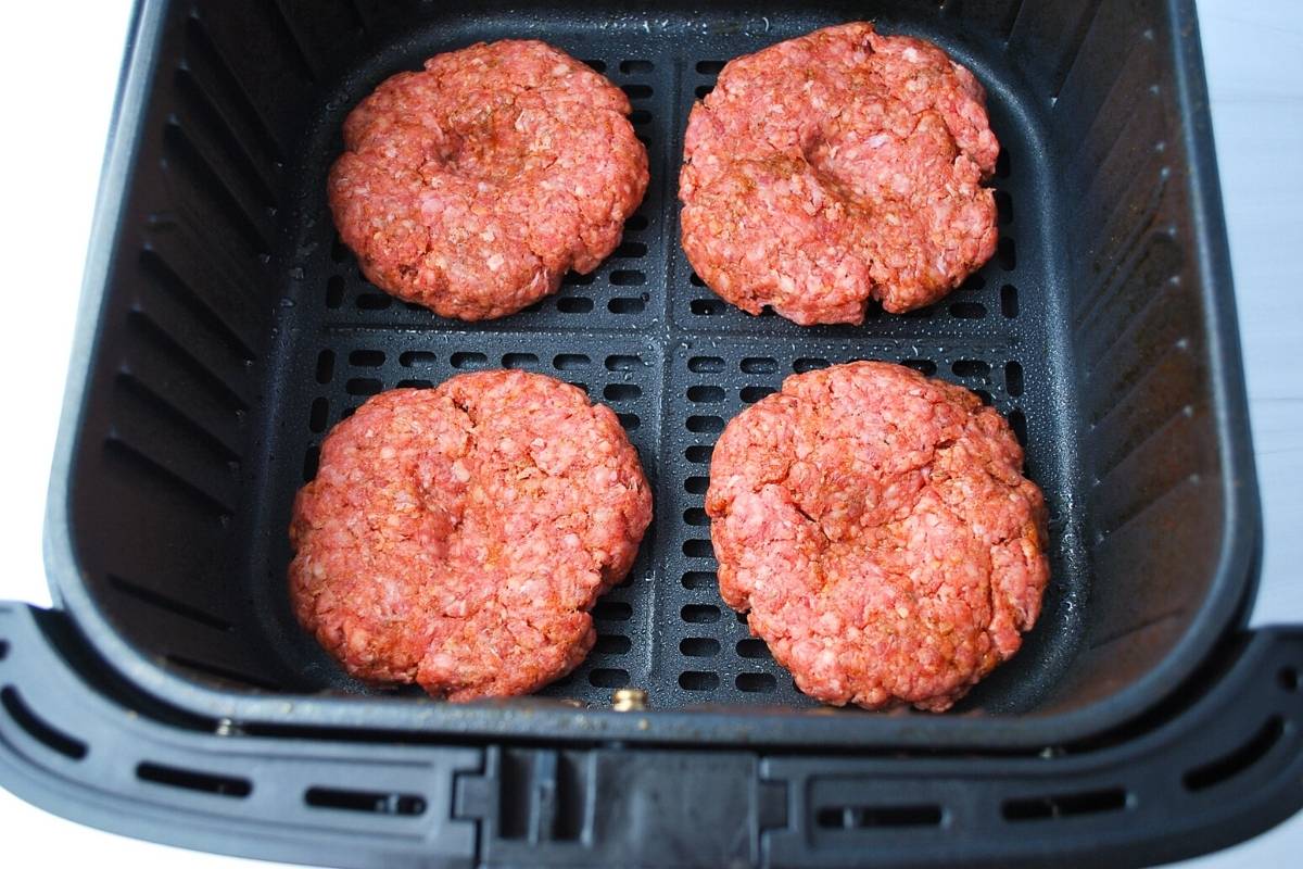 hamburger patties in an air fryer ready to cook