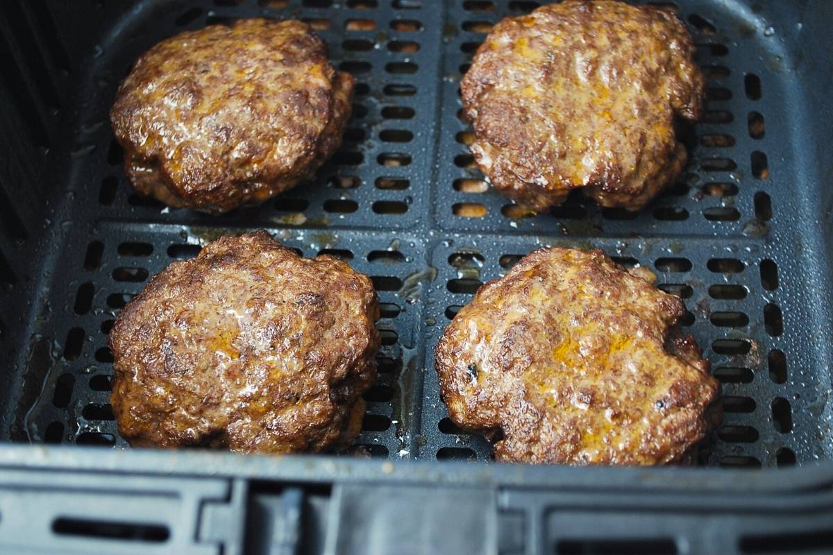 cooked hamburgers in an air fryer basket