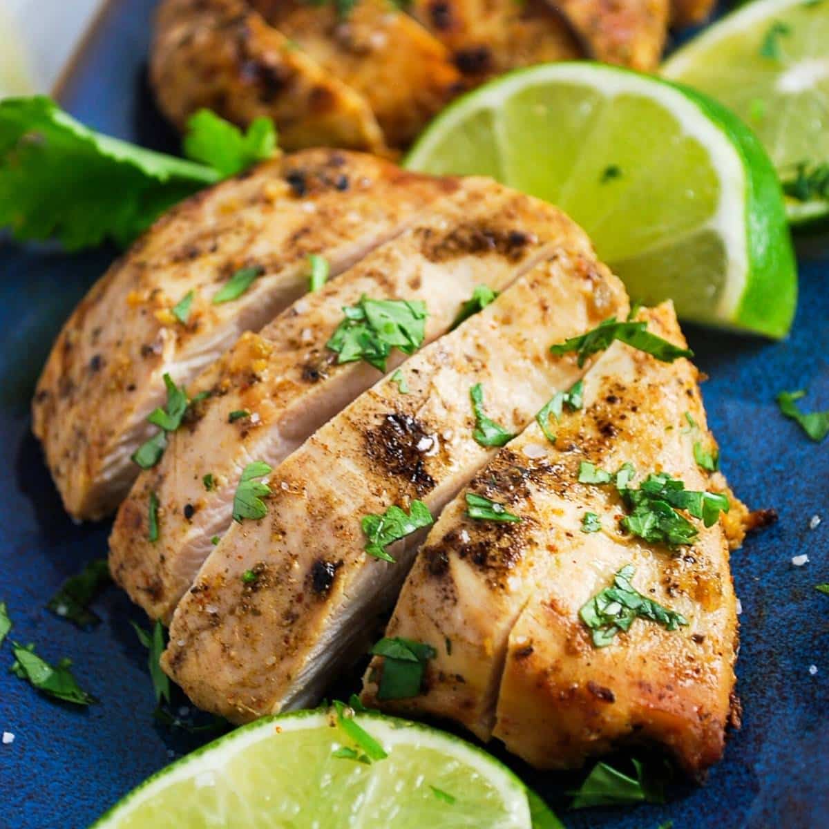 close up of sliced grilled chicken that was marinated in Mexican chicken marinade with fresh lime wedges