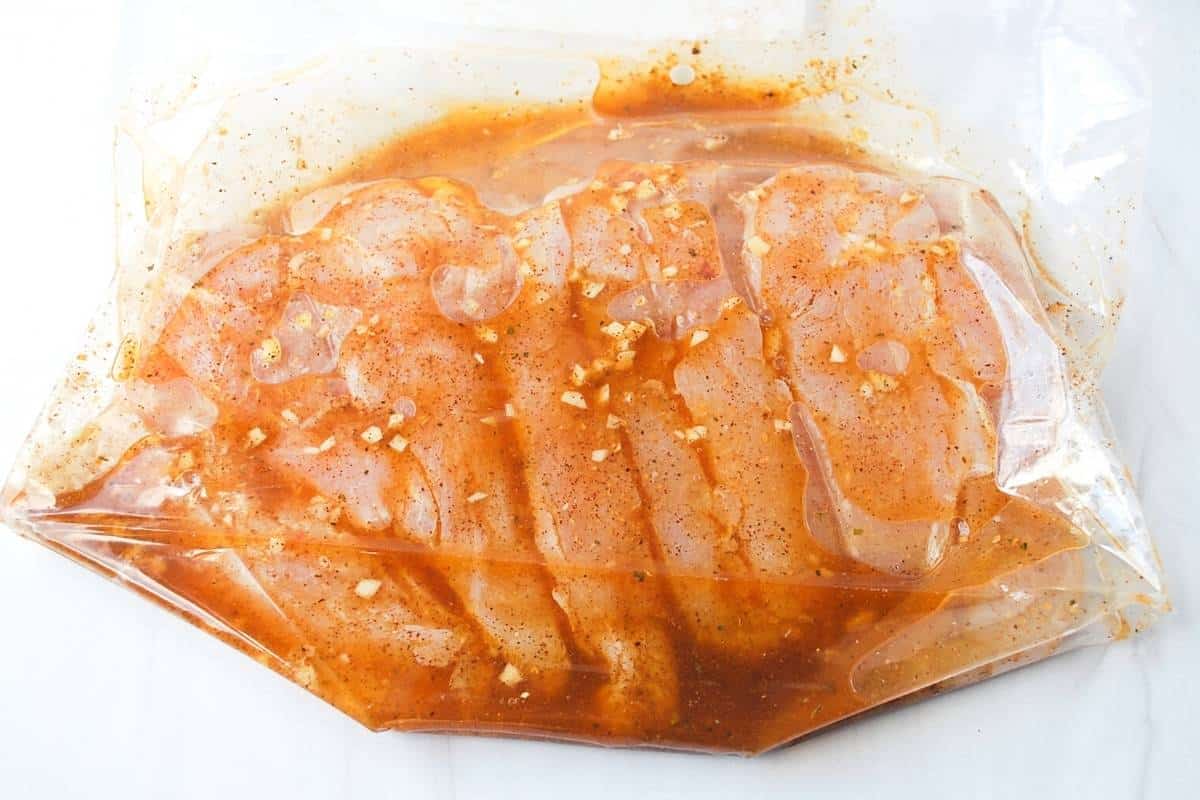 chicken marinating in a clear zip top bag
