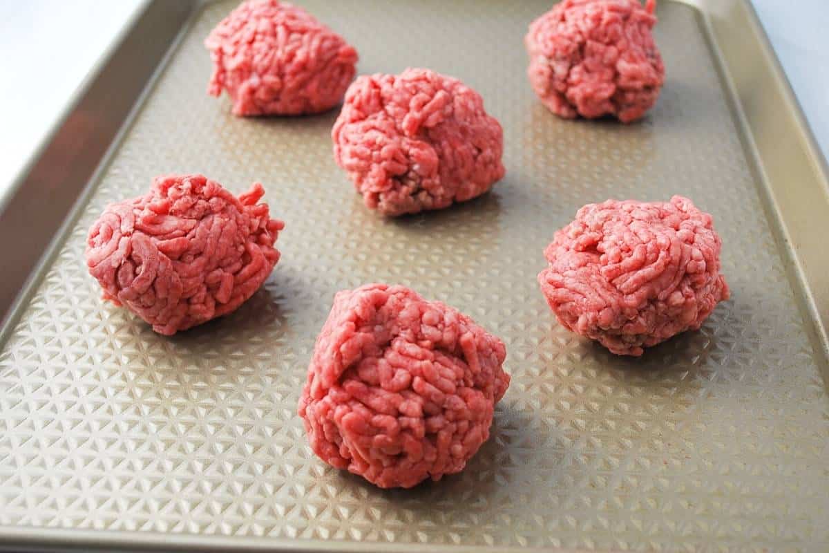 ground beef rolled into 3 oz balls on a cookie sheet