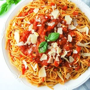 close up photo of a bowl of spaghetti arrabiata with fresh basil and cheese