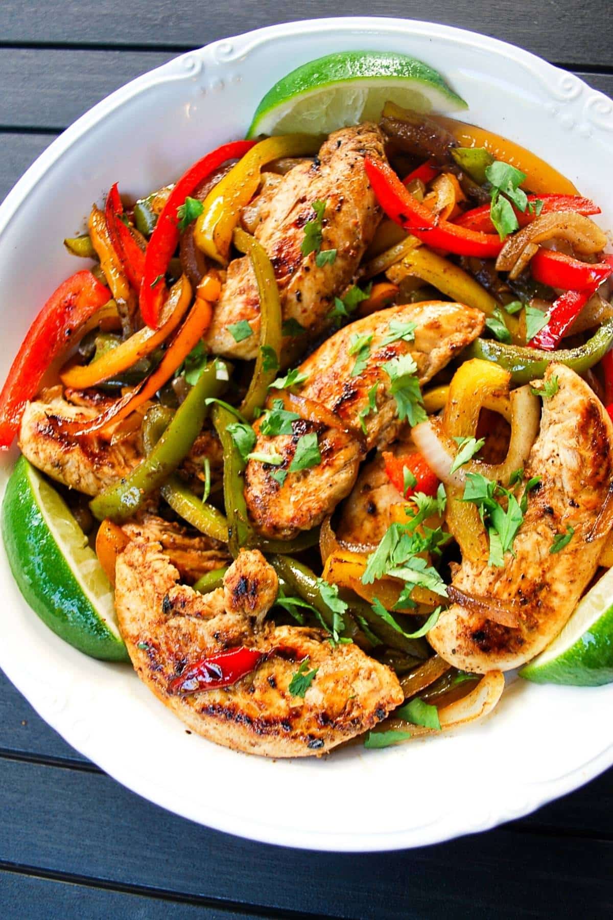 chicken fajitas in a serving bowl with lime wedges