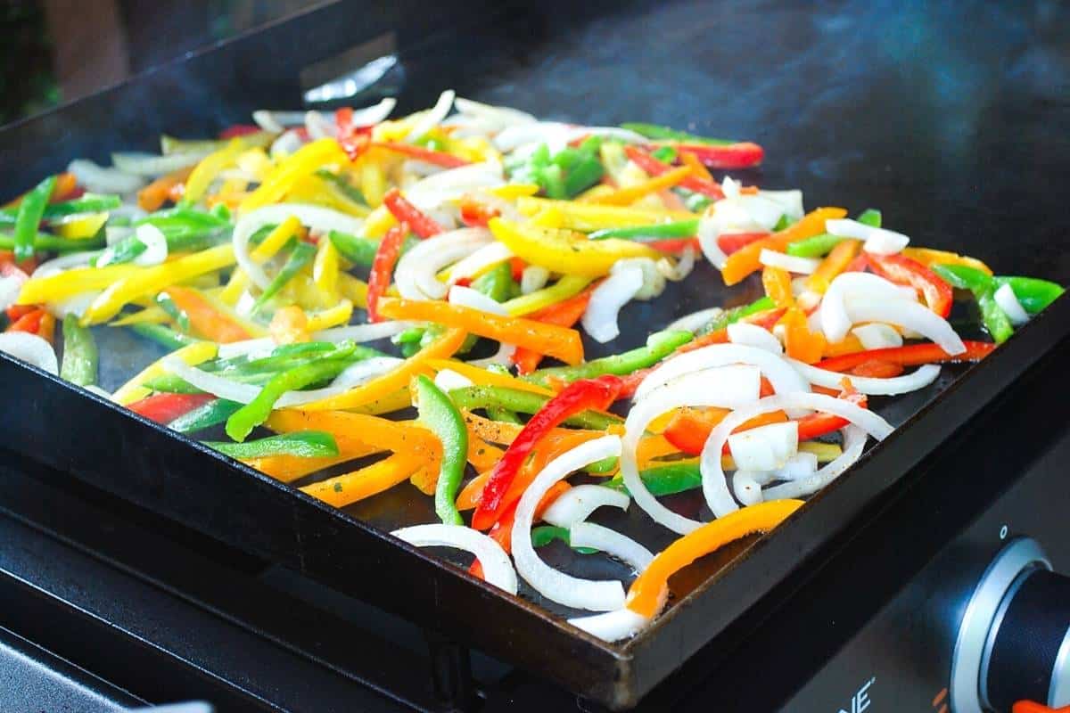 fajita veggies cooking on a flat top grill