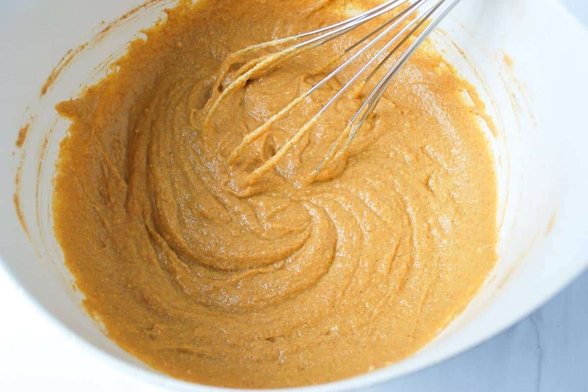 mixed pumpkin muffin batter in a bowl with a whisk
