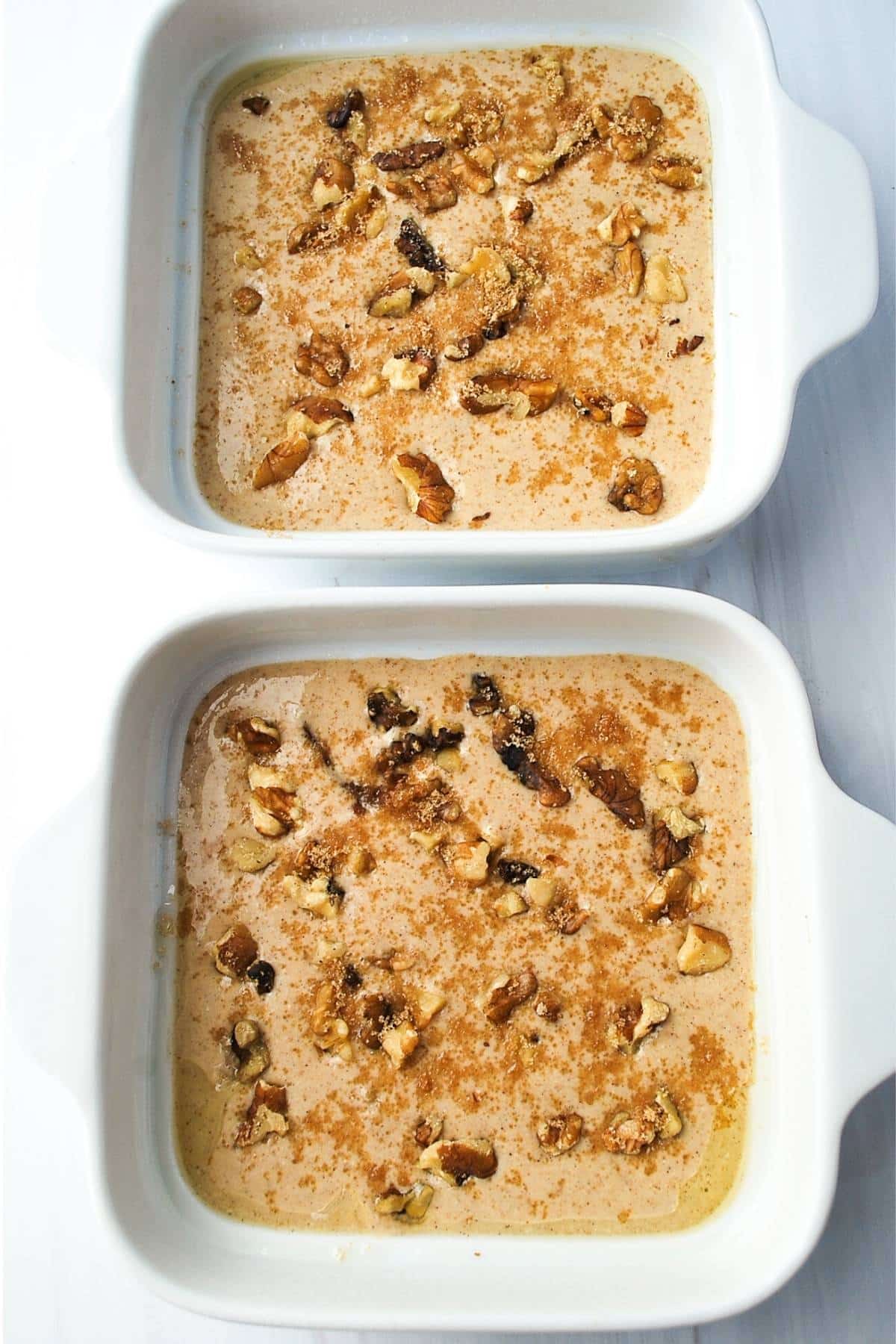 apple pie baked oats batter in 2 baking dishes topped with nuts and brown sugar