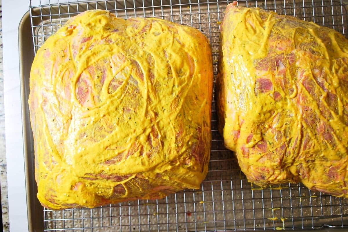 two pork shoulder butts covered in yellow mustard
