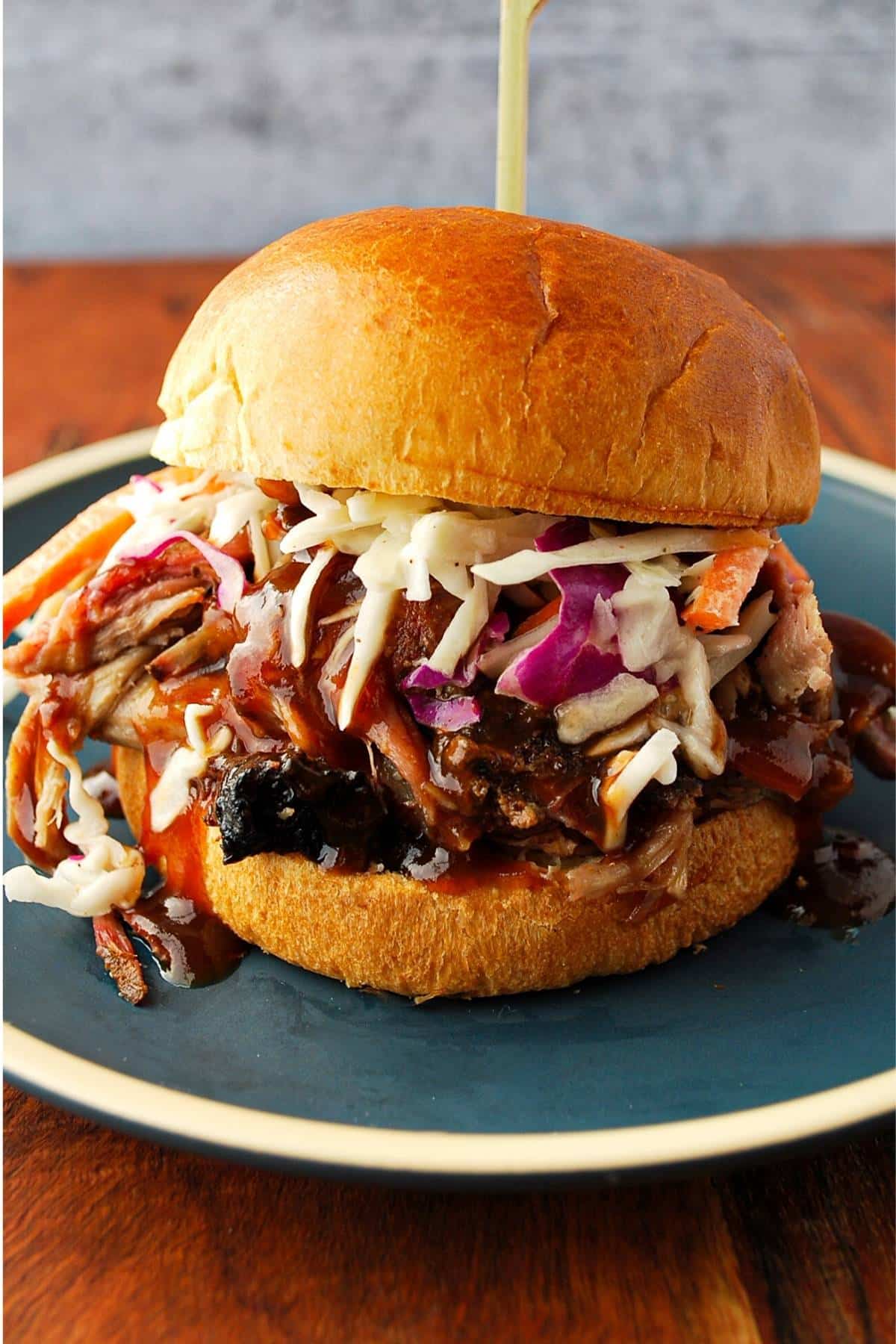 a pork bbq sandwich with slaw on a brioche bun on a blue plate