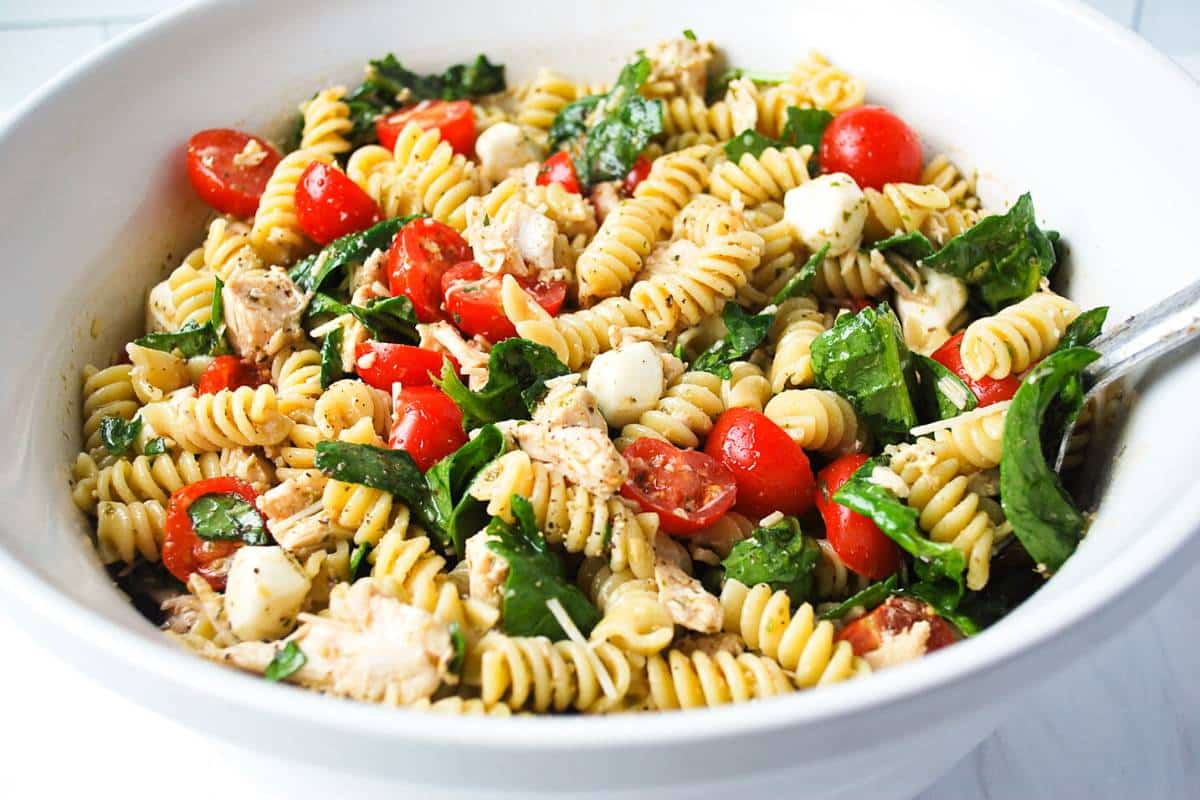pasta salad in a white bowl with a spoon