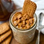 looking down at a jar of biscoff overnight oats with cookie butter and a crumbled Biscoff cookie on top and a whole cookie dipped inside