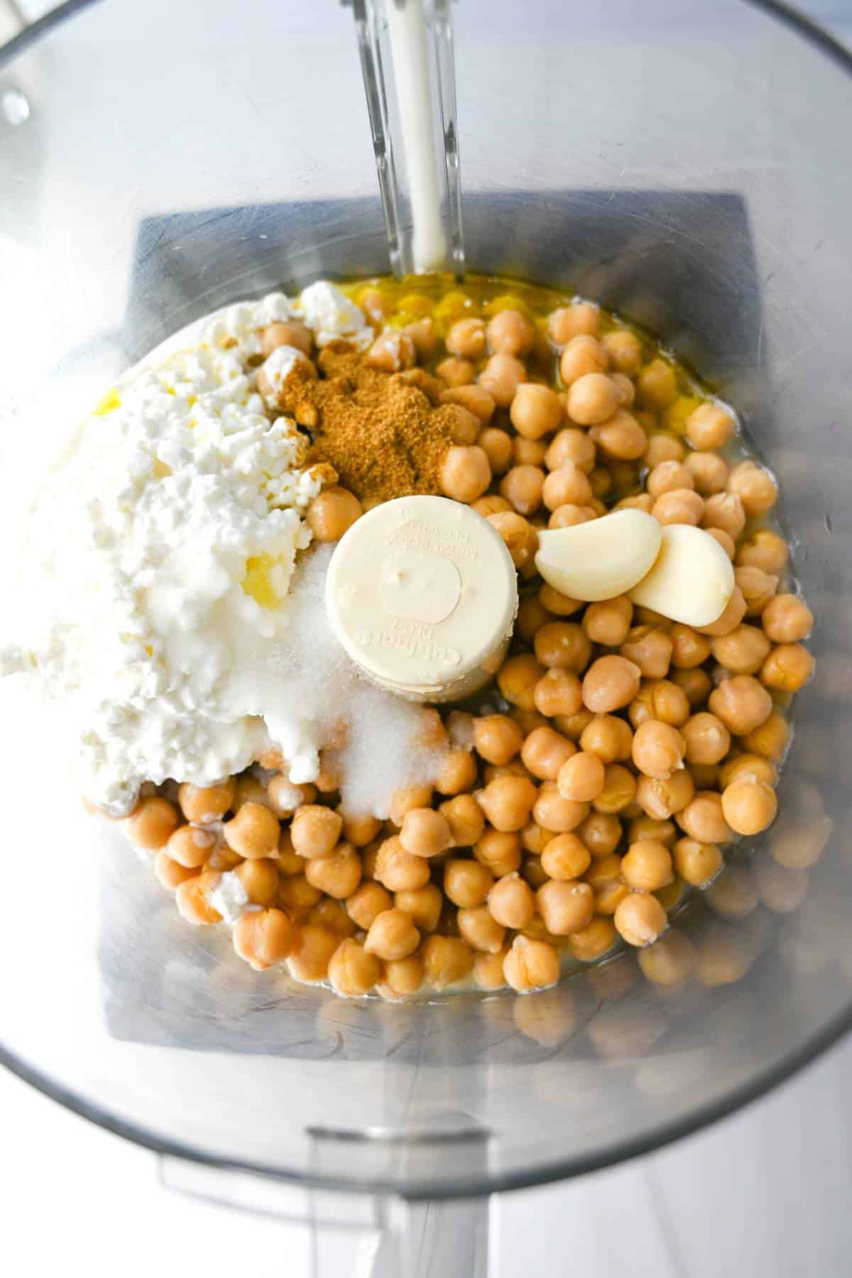 all the ingredients for protein hummus in a food processor ready to blend