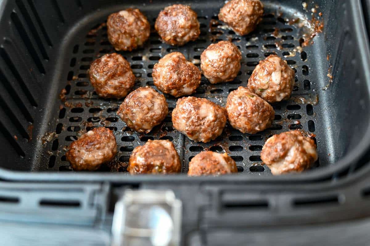 cooked bison meatballs in an air fryer basket