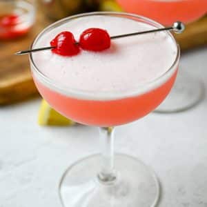 close up of a glass with a pink mocktail with cherries