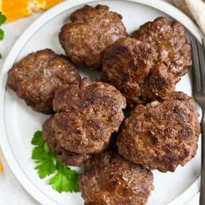 close up of lean beef sausage patties on a plate with parsley