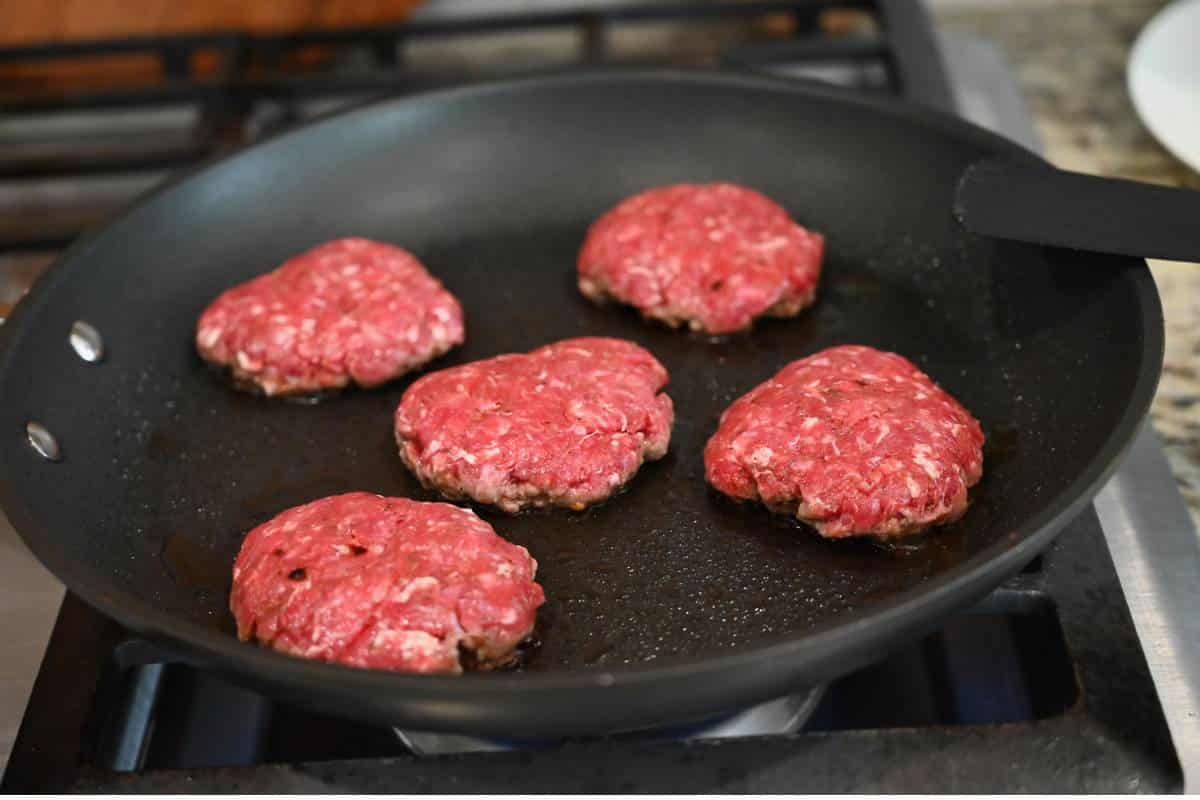 beef sausage patties cooking in a skillet