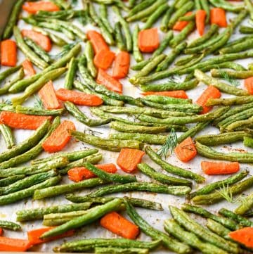 close up of a pan of roasted green beans with carrots and fresh dill