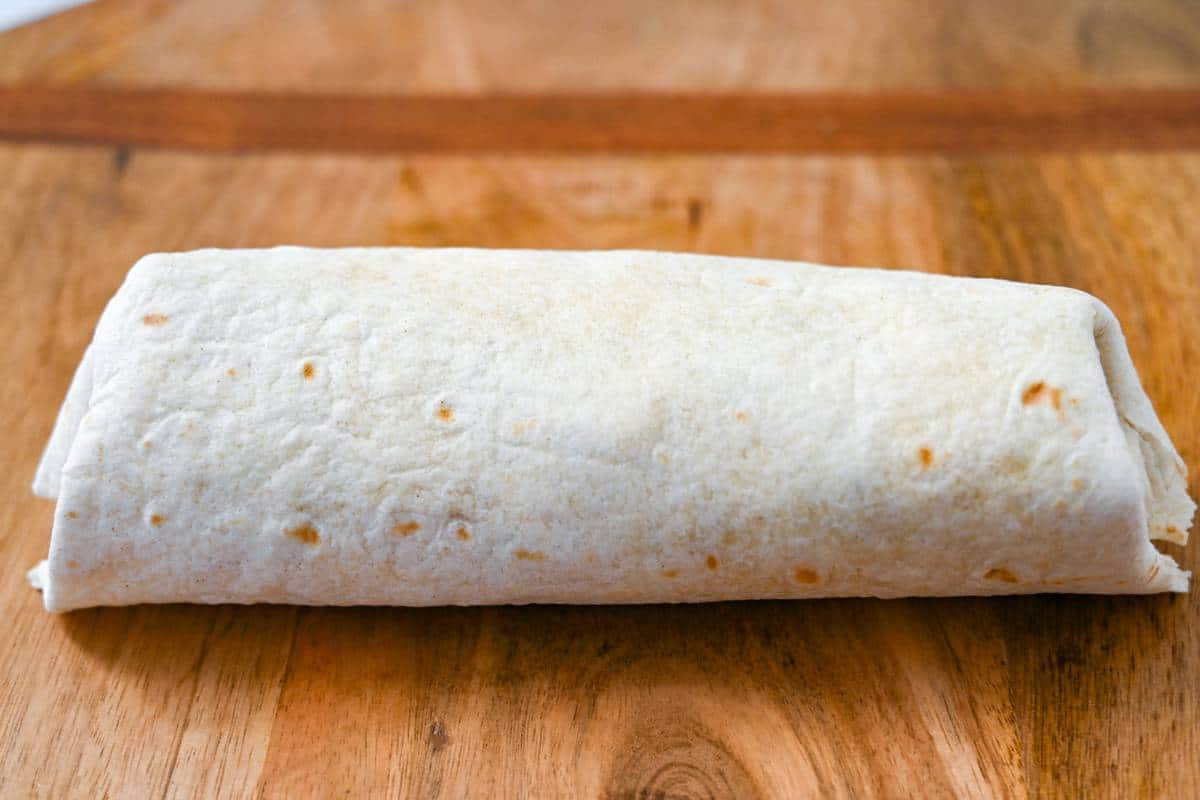 a rolled burrito on a cutting board