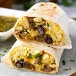 close up of a breakfast burrito slice in half and stacked with the inside showing sprinkled with fresh cilantro