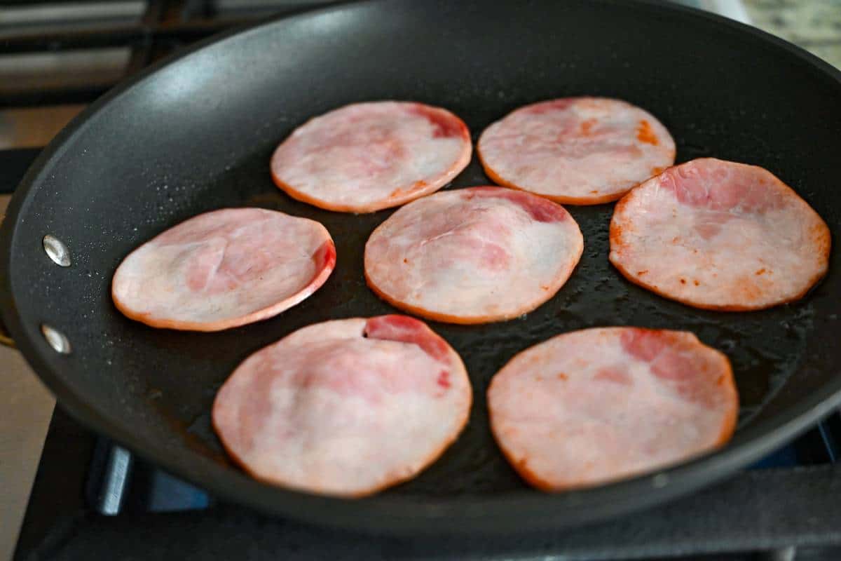 Canadian bacon cooking in a skillet