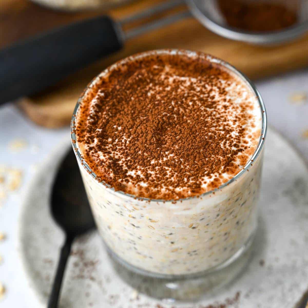 close up of the top of a jar of overnight tiramisu-inspired oats with a spoon on a plate