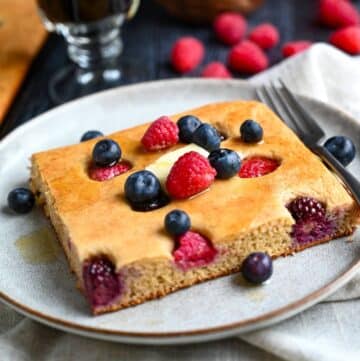 a slice of sheet pan pancake topped with butter and fresh berries