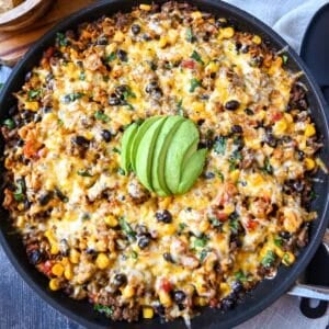 a taco skillet with melted cheese and sliced avocado