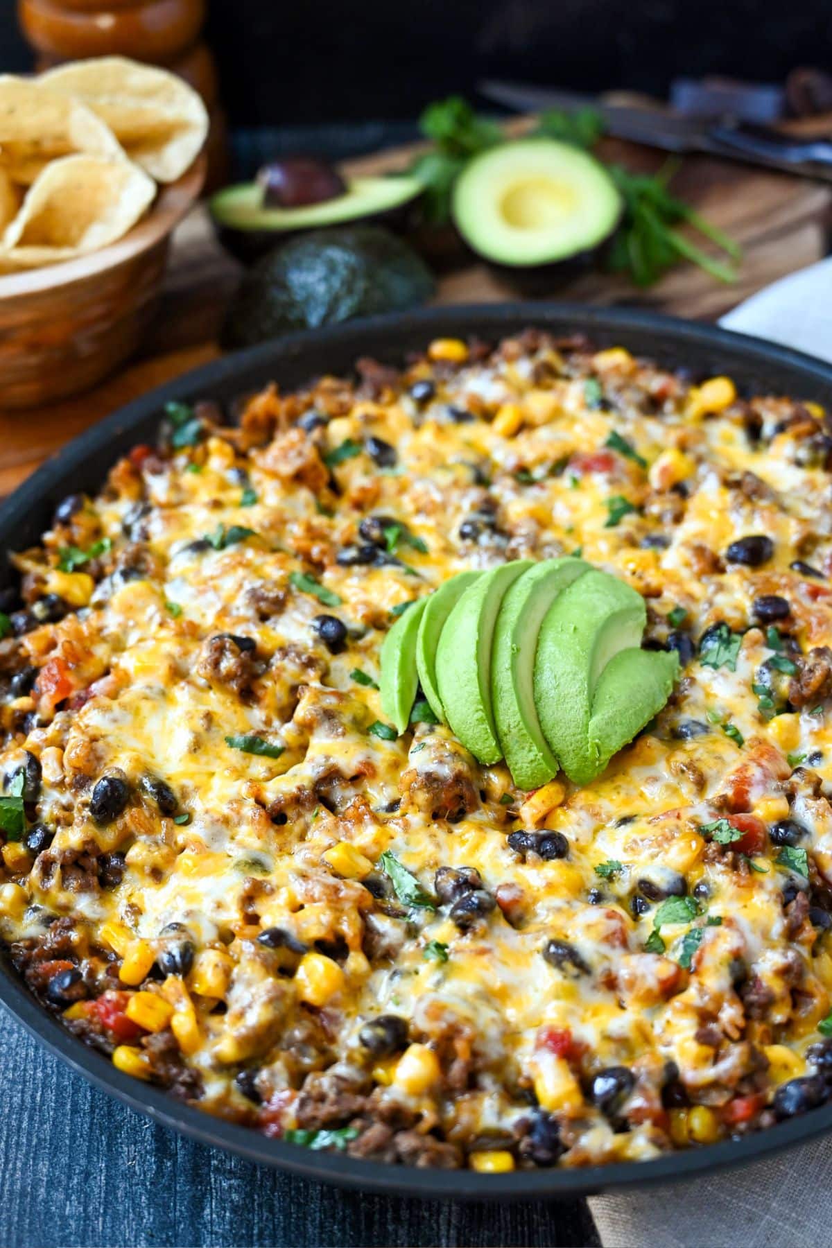 a loaded taco skillet meal with sliced avocados and chips
